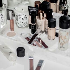 A makeup desk with various cosmetics including brushes, eyeshadow palettes, lipsticks, and a mirror, representing everyday beauty products.